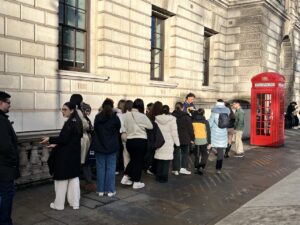 queue of people waiting to take photos in the parliament square phone box, london